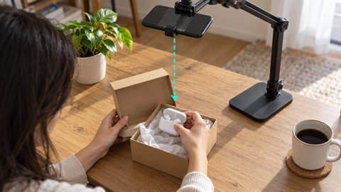 Unboxing Top-Down: Overhead phone view as hands open a package on a table.